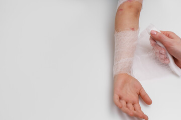 Woman's hand wraps a bandage around a child's hand. Copy space.