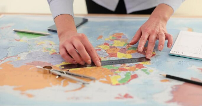Female hands with ruler and compass on world map