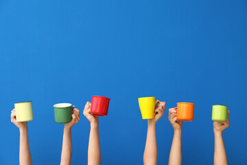 Women holding cups of hot coffee on blue background