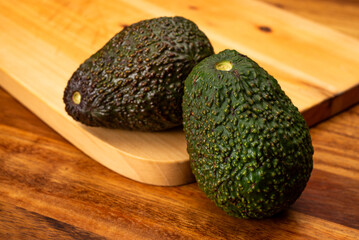 Two avocados on wooden table