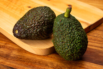 Two avocados on wooden table