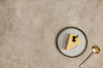 delicious Christmas pudding with blueberries on saucer near tea spoon on grey textured backdrop