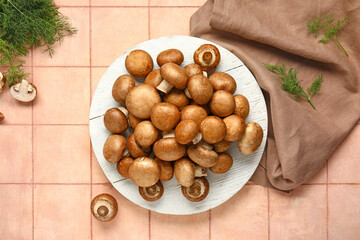 Plate with fresh mushrooms and dill on pink tile background