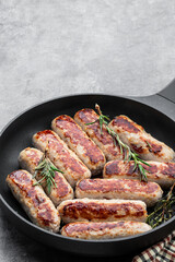 Delicious pork sausages in a frying pan on gray background