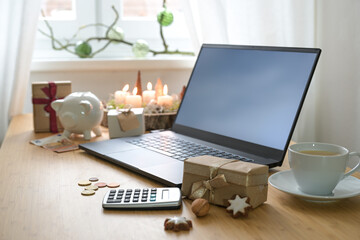 Christmas gifts, laptop and calculator on a decorated desk, economical holiday online shopping on a...