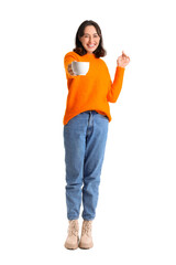 Young woman in warm sweater with cup of hot tea on white background