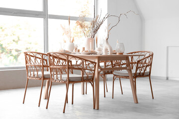 Elegant table setting with candles, dried flowers and glasses in light dining room