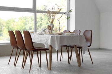Elegant table setting with dried flowers, candles and plates in light dining room