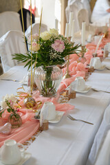 wedding decorations. We set the wedding table with decorative fresh flowers, details of the holiday. flower arrangement, plates and candles in a candlestick. Holiday, event