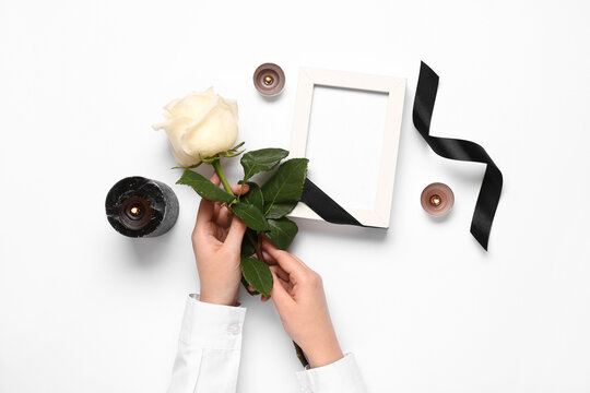 Female hands with rose, candles and photo frame on white background