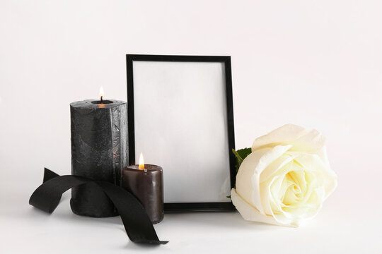 Black photo frame with candles and rose on white background