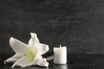 Beautiful lily and burning candle on black table