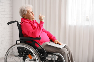 Senior woman in wheelchair with laptop at home