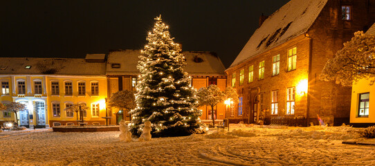 Snowmans near Christmas tree.View of market square with decorated Christmas tree covered with snow...