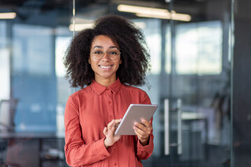 Portrait young successful businesswoman with tablet computer in hands inside office at workplace,...