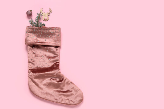 Christmas sock with fir branch and beautiful decorations on pink background