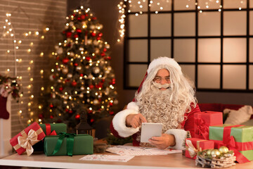 Santa Claus using tablet computer at home on Christmas eve