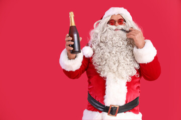 Santa Claus with smoking pipe and bottle of champagne on red background