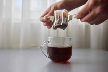 The process of brewing coffee. Water is poured into a drip coffee bag in a mug. Trends in brewing...