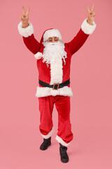 Cool Santa Claus showing victory gesture on pink background