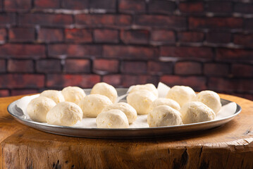 Cheese bread, pan with raw cheese breads ready to go in the oven, on rustic wood, selective focus.