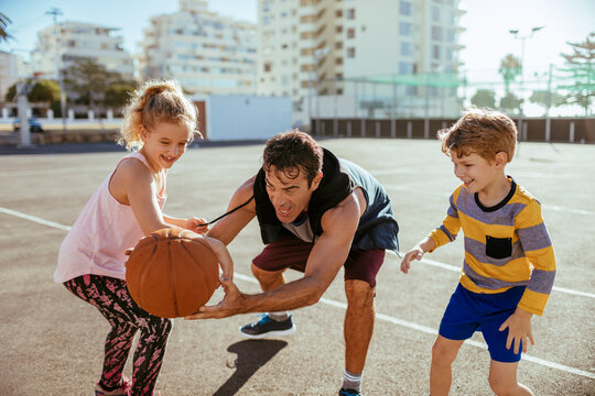 Single father playing basketball with his kids at the basketball park