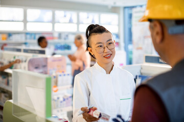 Pharmacist Providing Medication to Customer at Local Drugstore