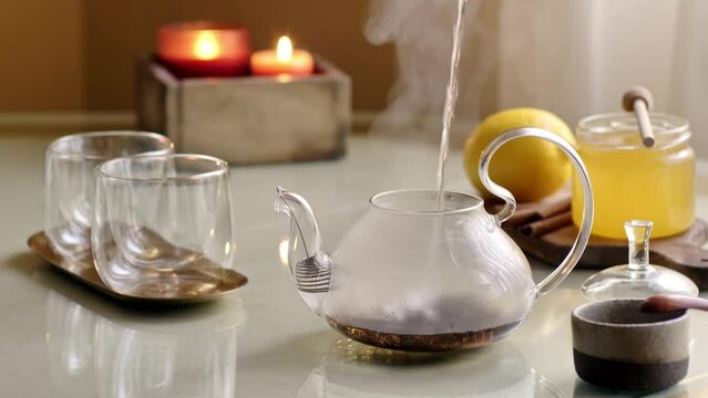 Pour hot water with steam into transparent pot preparing black tea. 4K video