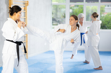 Women in white kimonos are engaged in wrestling at sports training. Woman paired up with female...