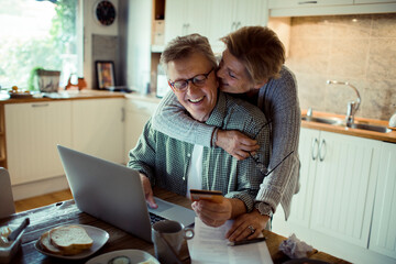 Middle aged couple holding credit card in the kitchen