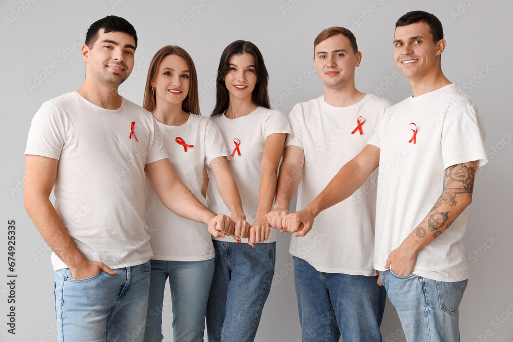 Canvas Prints Group of young people with red ribbons putting hands together on grey background. World AIDS day concept