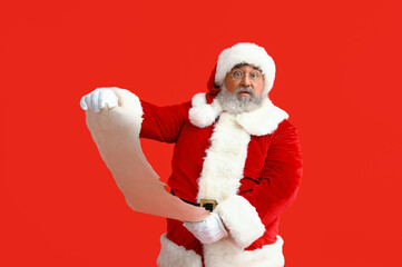 Surprised Santa Claus reading letter on red background