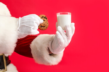 Obraz na płótnie Canvas Santa Claus with glass of milk and cookies on red background