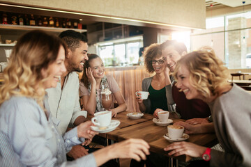 Group of happy friends having coffee in cafe