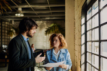 Young businesswoman reading document with colleague in office