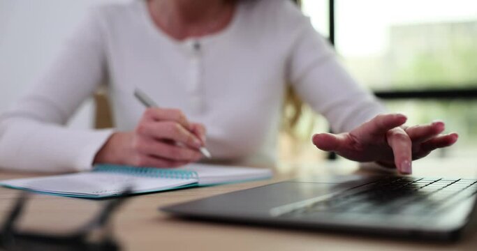 College student businesswoman using laptop computer at desk and diary to take notes