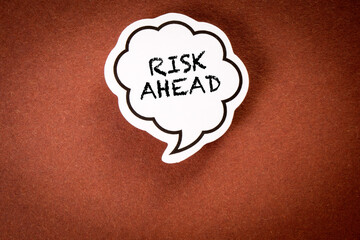 RISK AHEAD. Speech bubble with text on brown background