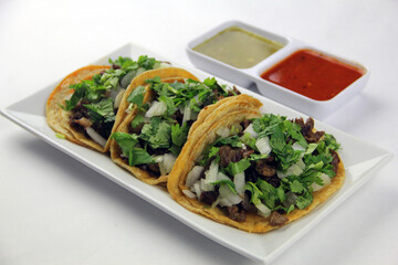 3 Steak Tacos on a Plate with Cilantro and Onion on Corn Tortilla Upper Side View
