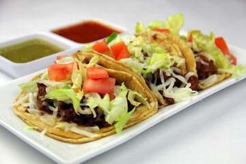 3 Beef Tacos on a Plate with Tomato Lettuce on Corn Tortilla Top View