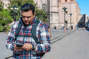 Plus sized mexican tourist looking at his phone in San Luis Potosi city, copy space