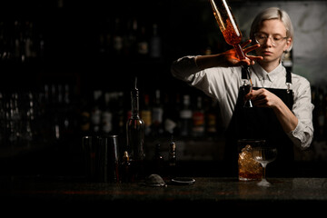Fototapeta na wymiar Female bartender fills a jigger with a drink from a geyser bottle
