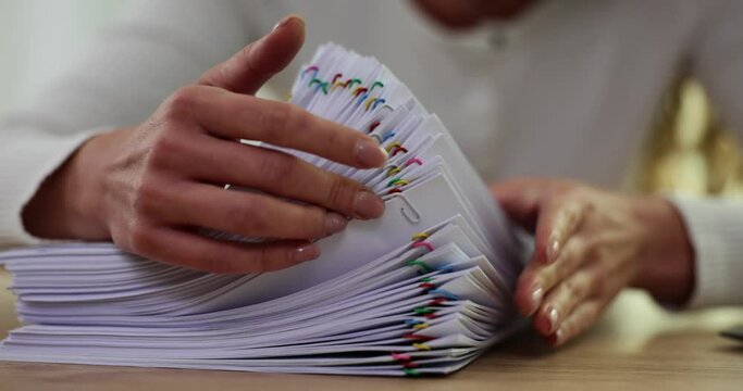 Female employee works with stacks of paper files for searching and checking