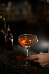 Female hand holds a cocktail glass with a cocktail by the stem
