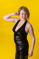 Portrait of curvy mature blonde in fashionable black party dress, questionable looking at camera