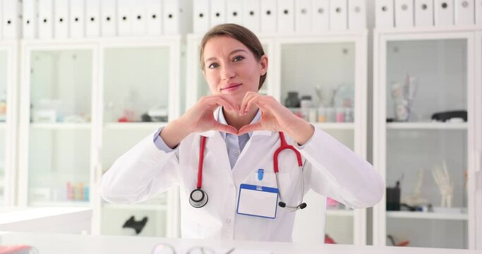 Portrait of a smiling young nurse or general practitioner showing heart love hand gesture