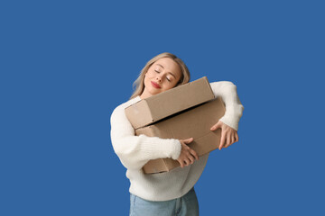 Obraz premium Young woman with cardboard boxes on blue background