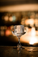 Cocktail glass on a stem with a large square piece of ice is on the counter