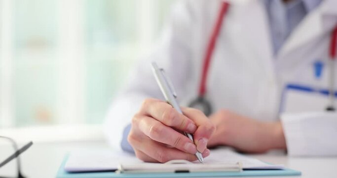 Female doctor holds pen and writes patient chart closeup