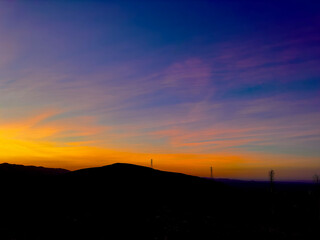 Sunset in the mountains, with utility poles, towers, electrical