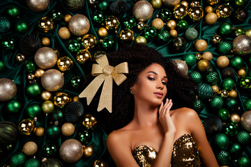 Beautiful girl with big golden bow in her hair giving herself as gift flirting lying dreaming on x-mas holiday baubles